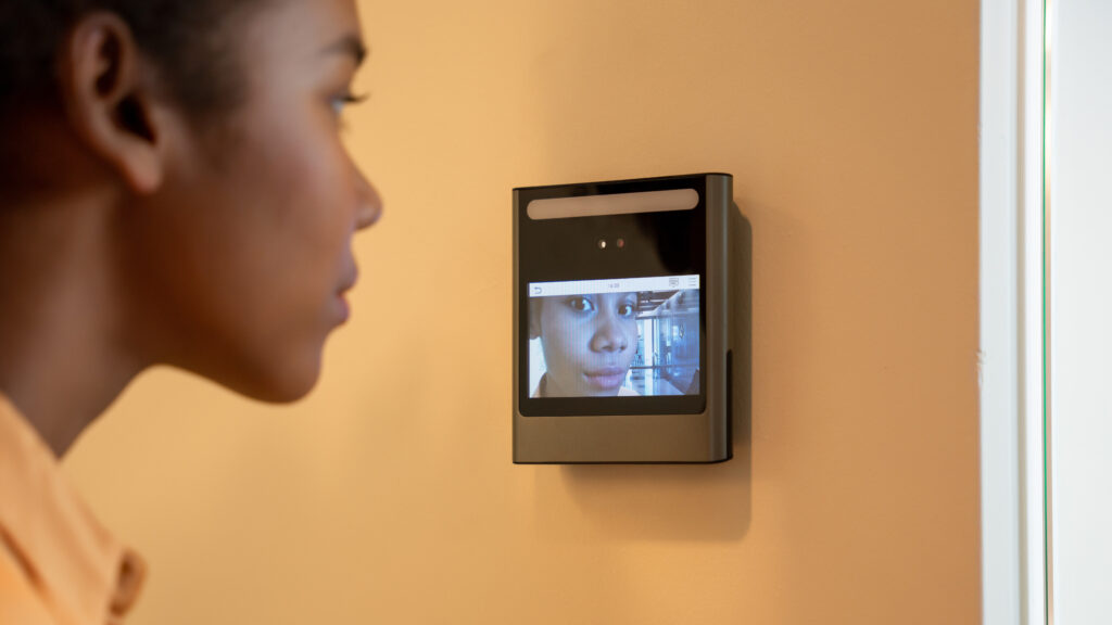 a face scanner being used by a woman to open a door at an office building. control device for security system. device to control a security system.